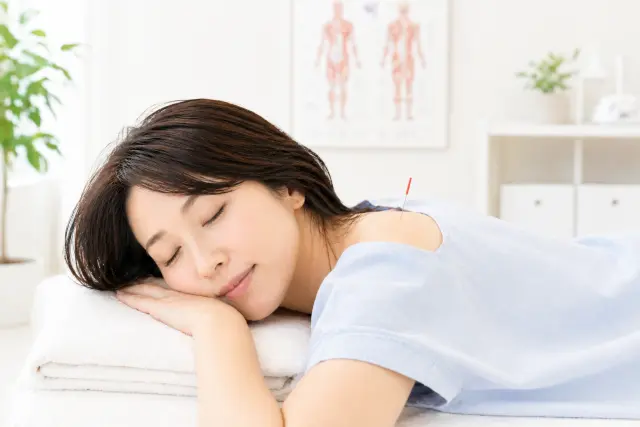 うつ伏せで鍼施術を受けている女性