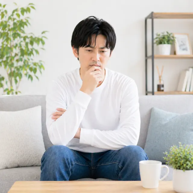 ソファーに座り顎に手を当てる男性
