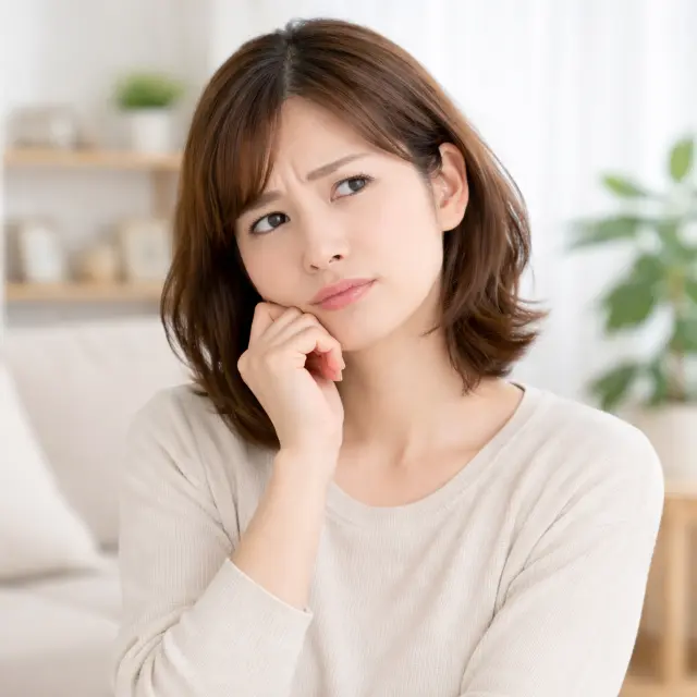 顔に手を当て考え込む女性