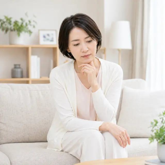 ソファーに座り顎に手を当てる女性
