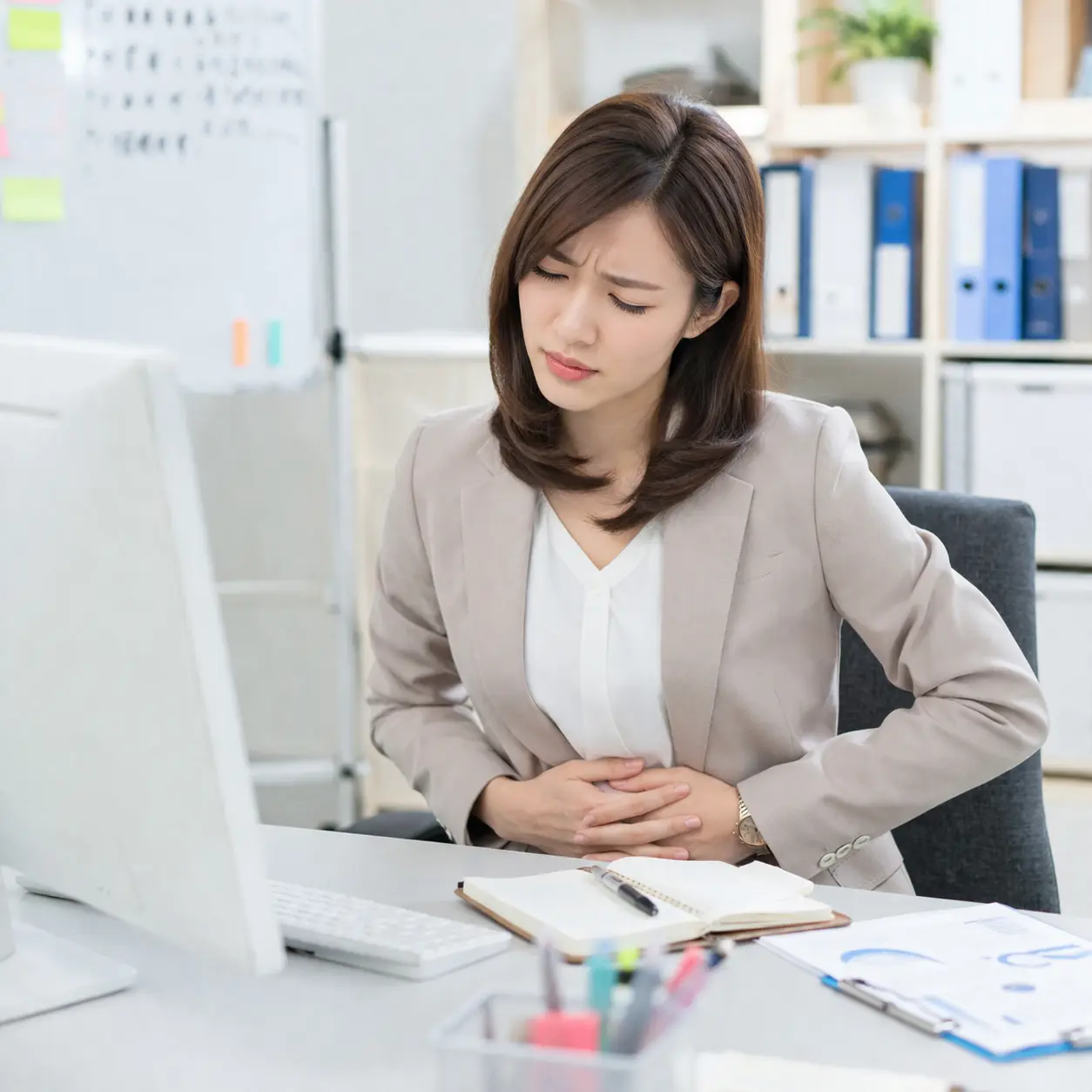 仕事中に下腹部の痛みを感じる女性