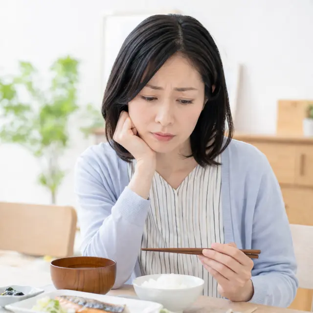 顎に手を当て料理を見ている女性