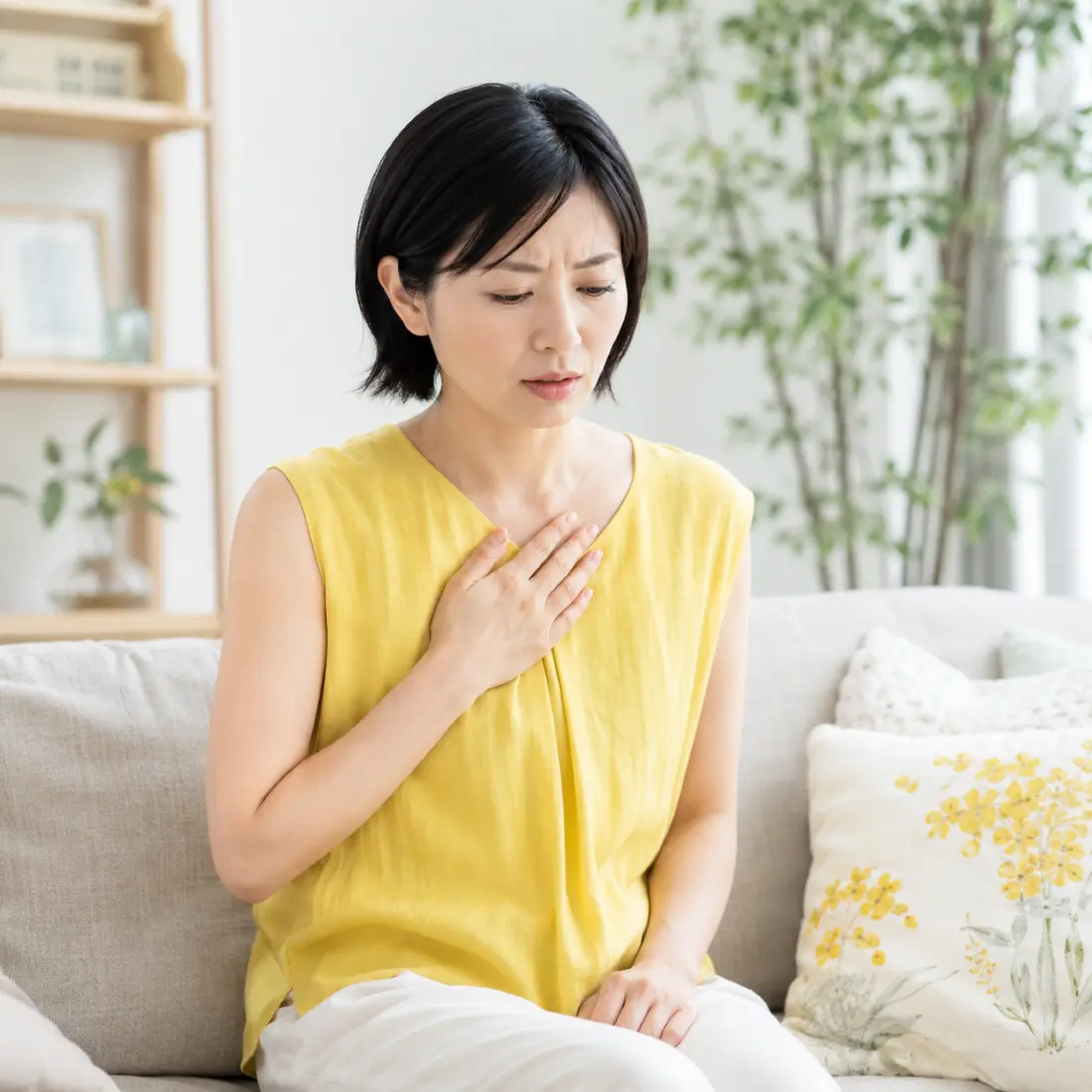 ソファーに座り胸に手を当てる女性