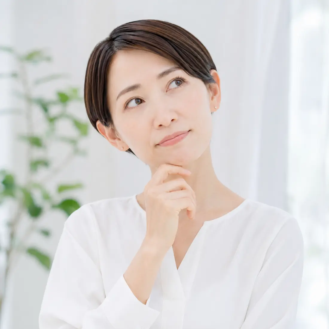 顎に手を当て首を傾ける女性
