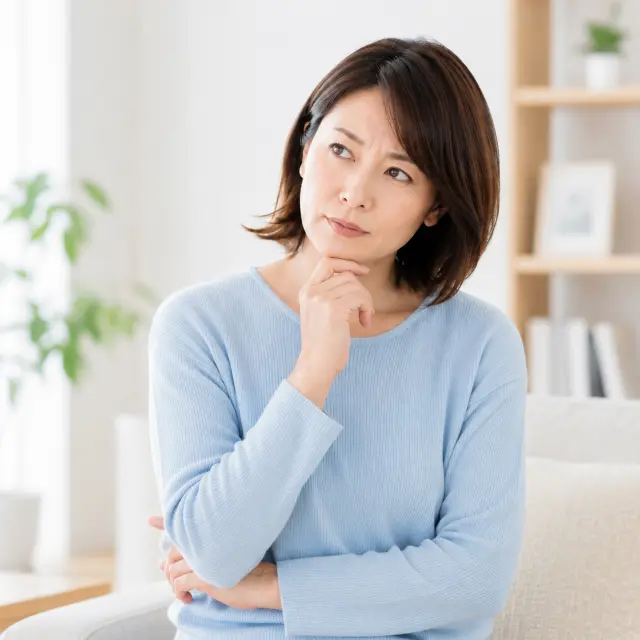 顎に手を当て首をかしげる女性