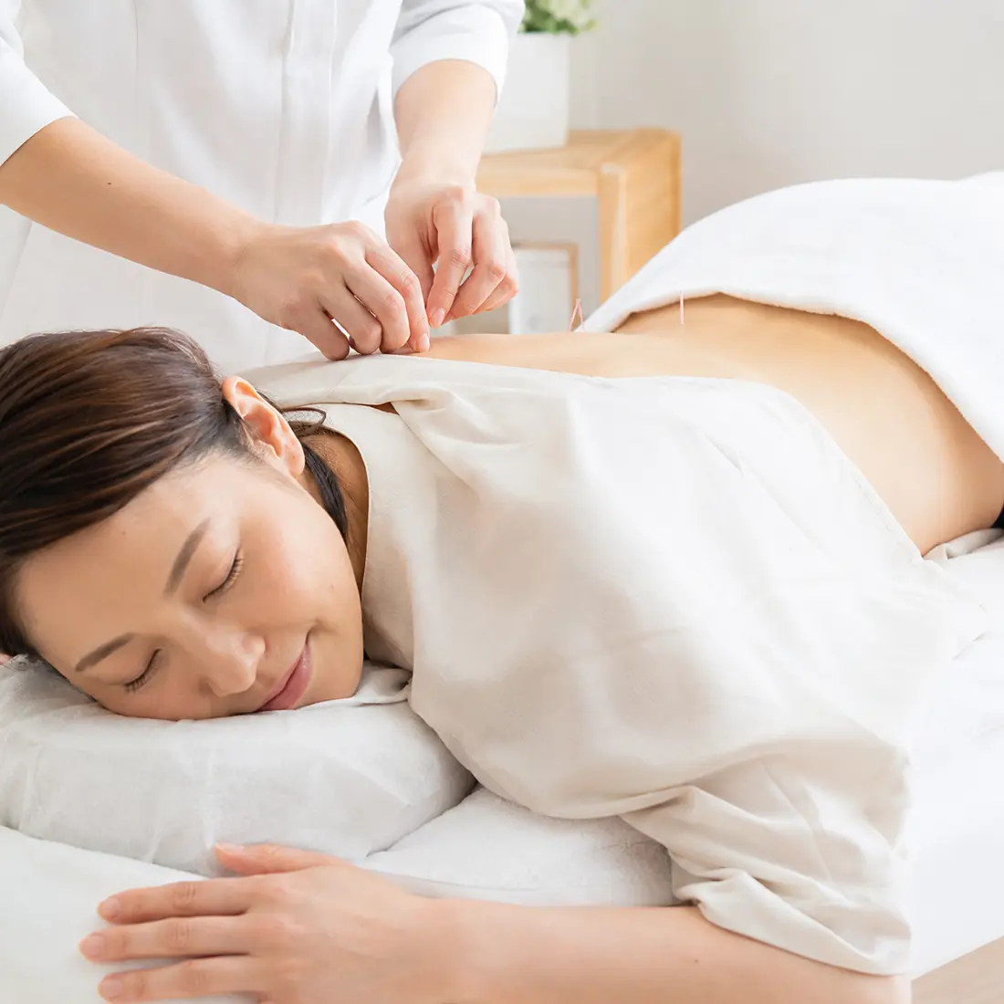 ベッドでうつ伏せになり施術を受ける女性
