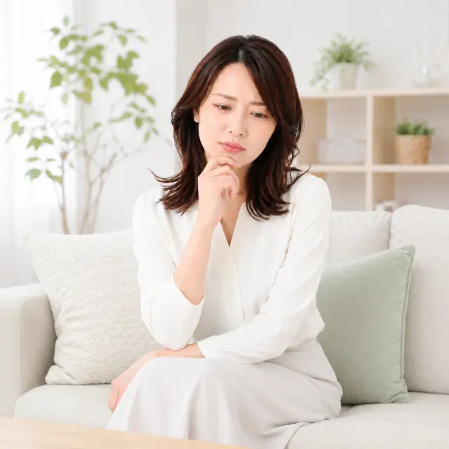 手を顎にあてうつむく女性