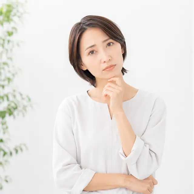 顎に手を当てて首を傾げる女性