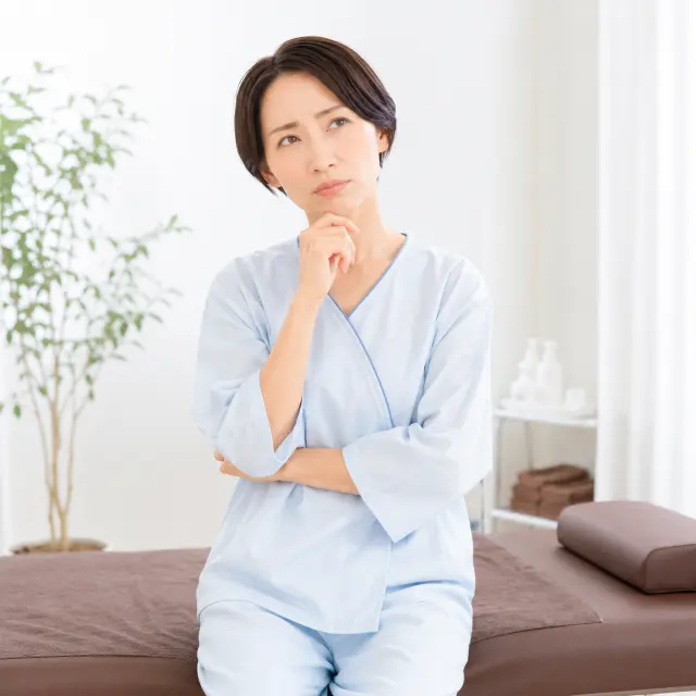 ベッドに座り顎に手を当てる女性