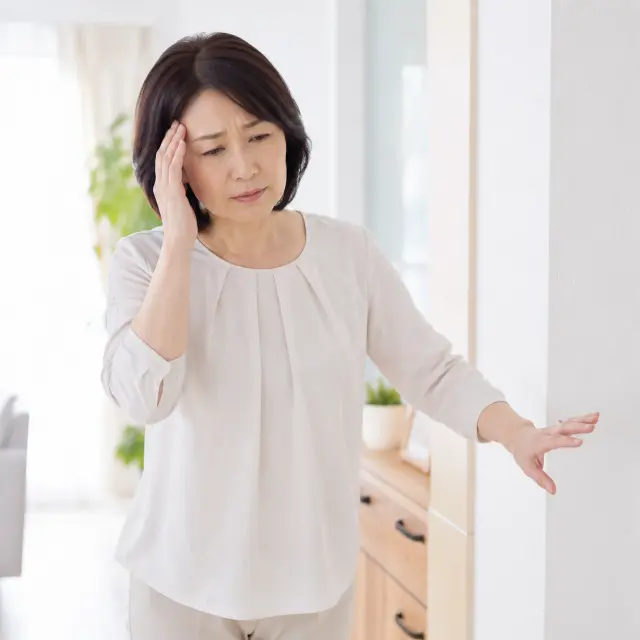 頭に手を当てる女性
