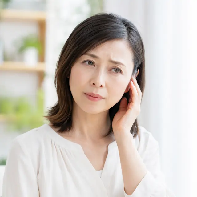 耳に手を当てる女性