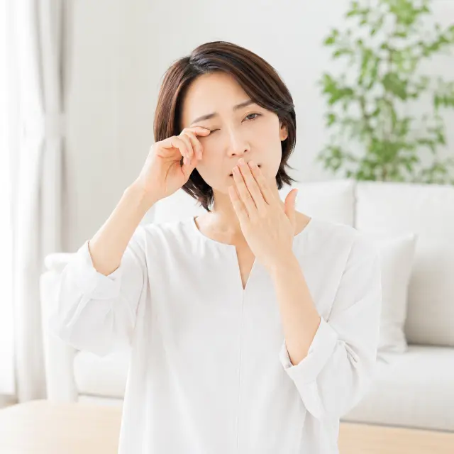 目と口に手を当てる女性