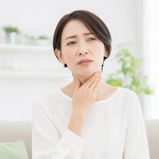 喉に手を当てる女性