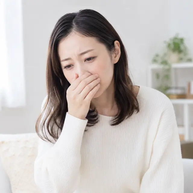 鼻に手を当てる女性