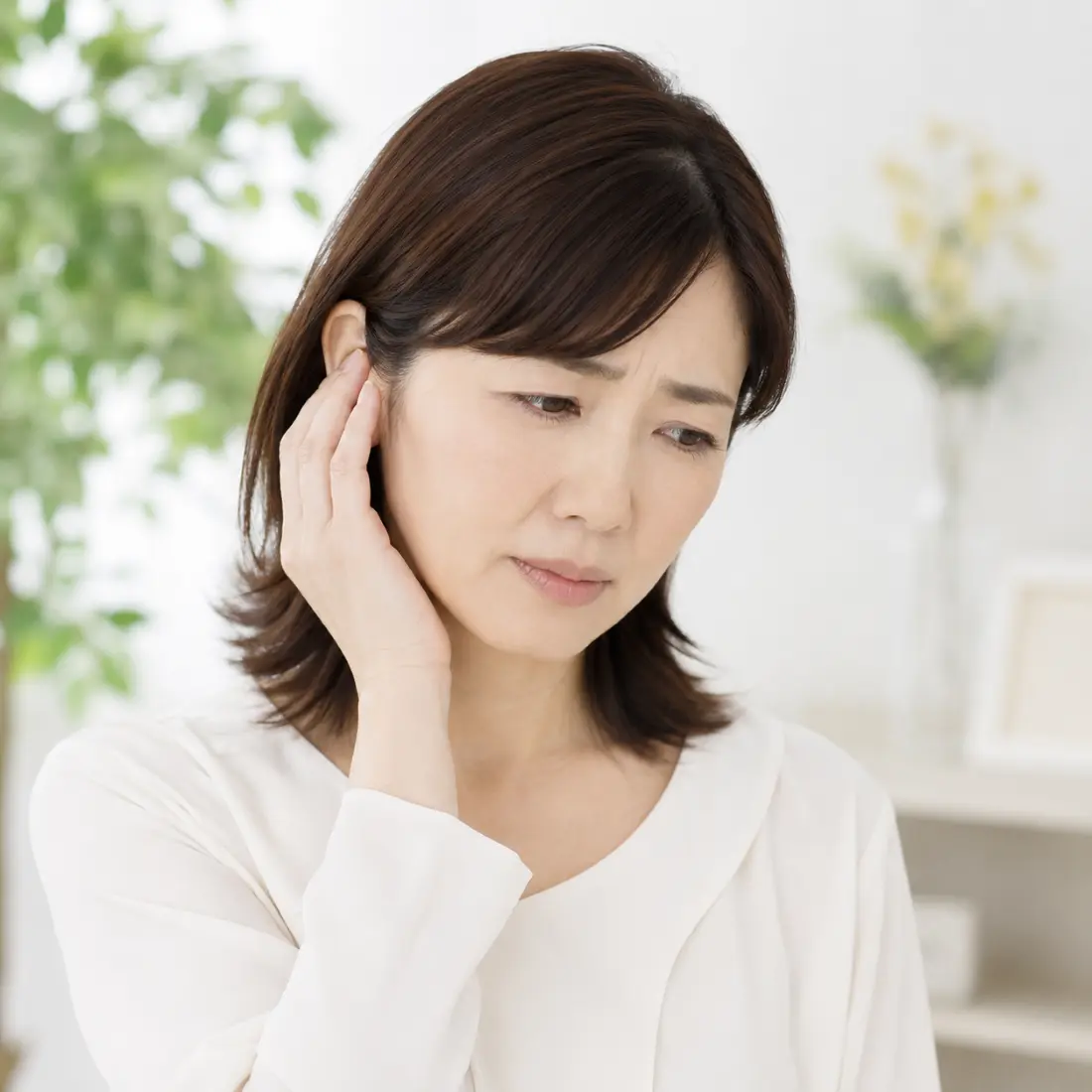 耳に手を当てる女性