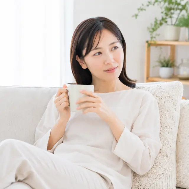 ソファーに座りマグカップを持つ女性