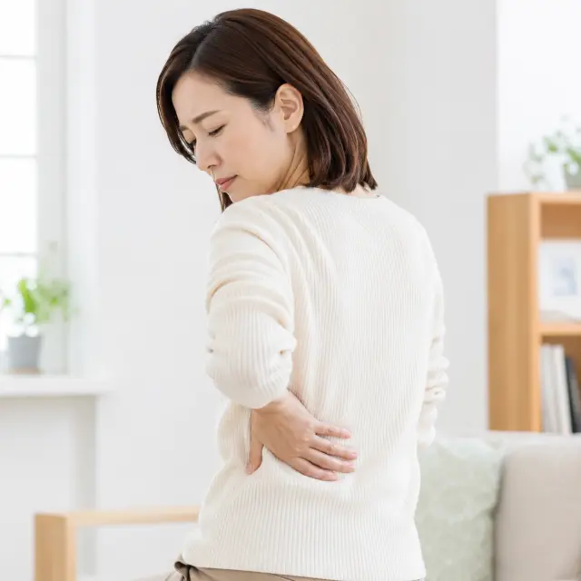背中に手を当てる女性