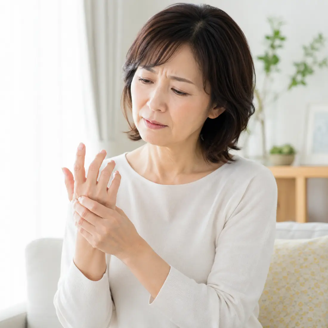 ソファーに座り手を触る女性