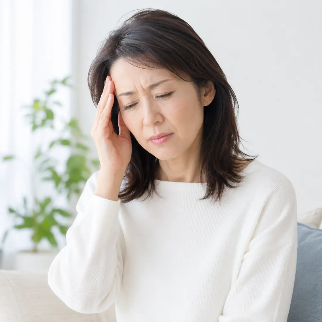 こめかみに手を当てる女性