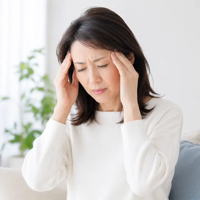両手でこめかみに手を当てる女性