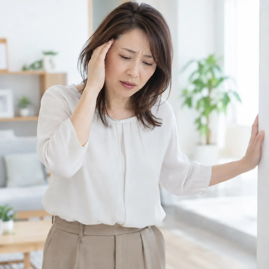 こめかみに手を当てる女性