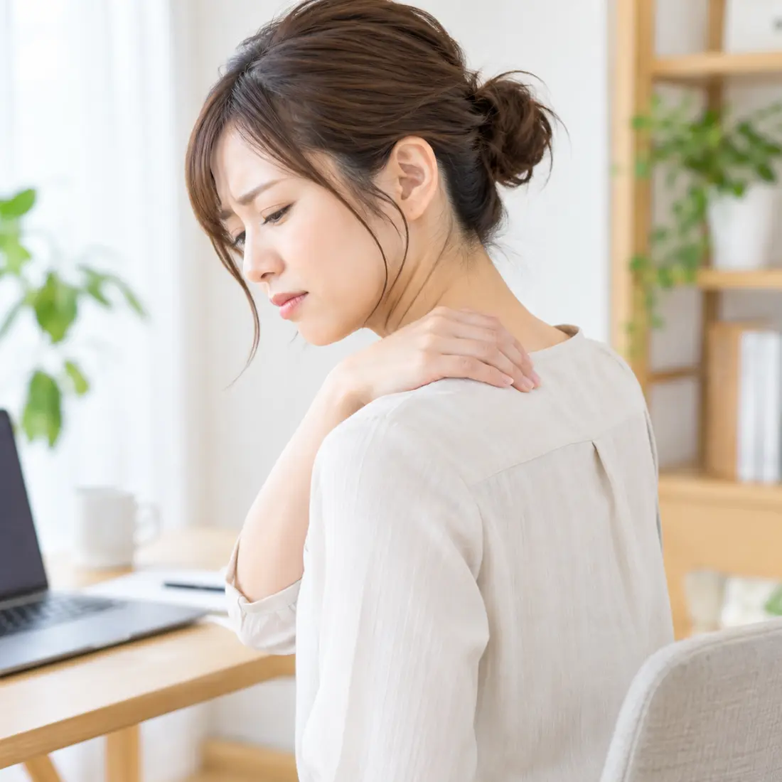 左肩に手を当てる女性